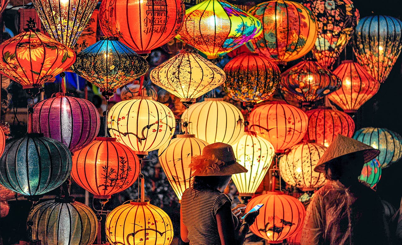 People standing under colorful lanterns at a night market, symbolizing cultural and social pressures tied to perfectionism