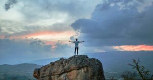 Person on rock with arms spread.