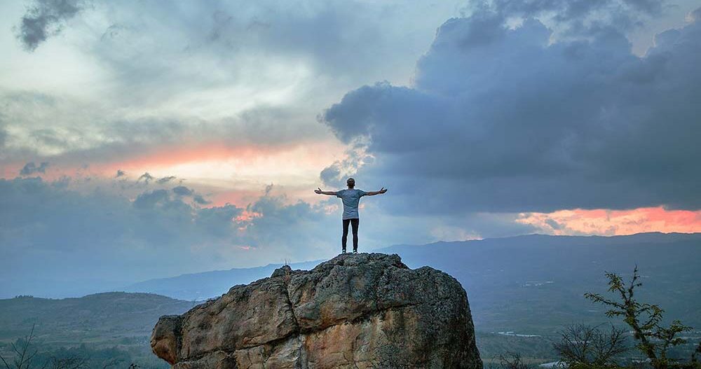 Person on rock with arms spread.