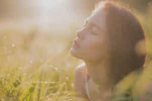 Woman resting peacefully in sunlight with eyes closed, representing inner calm and emotional release.
